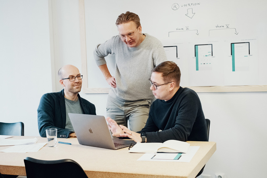 Kolme miestä tietokoneen ääressä